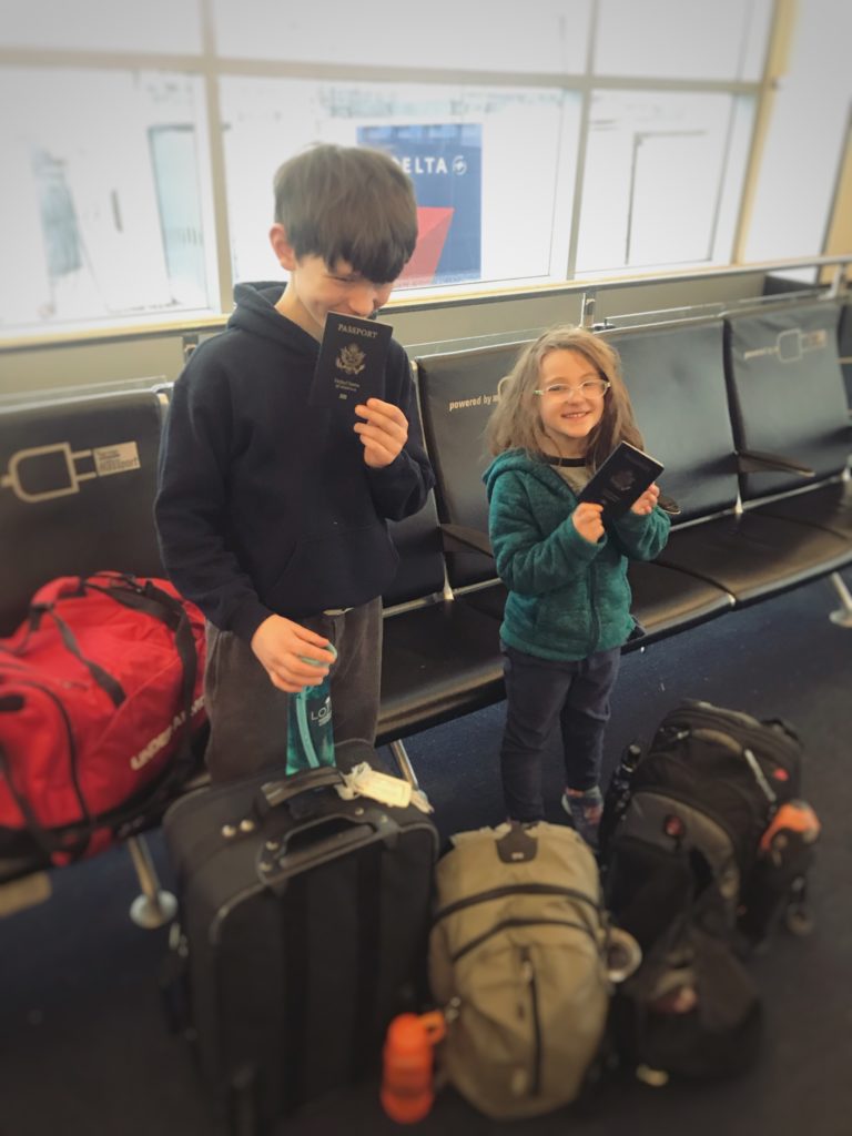 Kids with passports and luggage at Delta Terminal - flying with kids | RealLifeWithDad.com