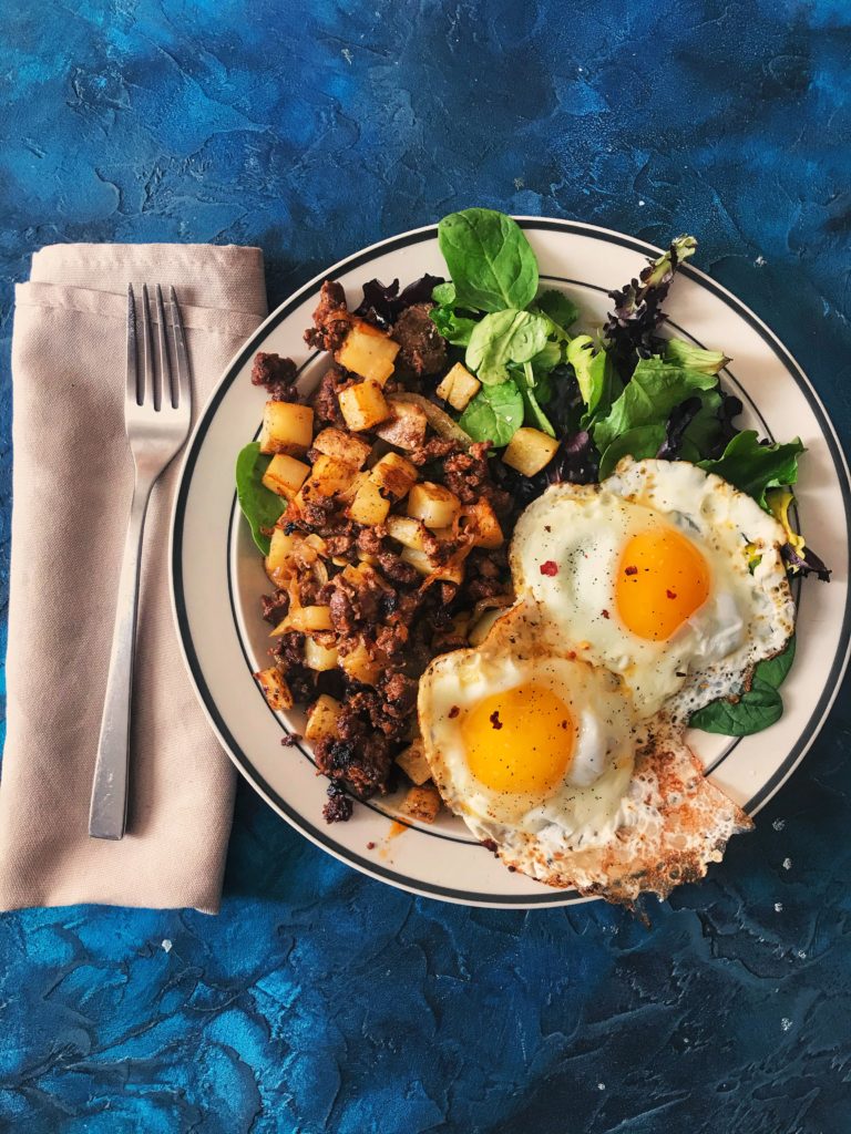 Chorizo hash with sunny side up eggs over salad greens. This looks so good!