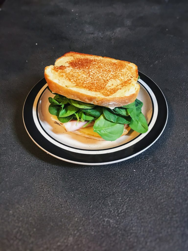 White bread made into a grilled sandwich with ham cheese and spinach