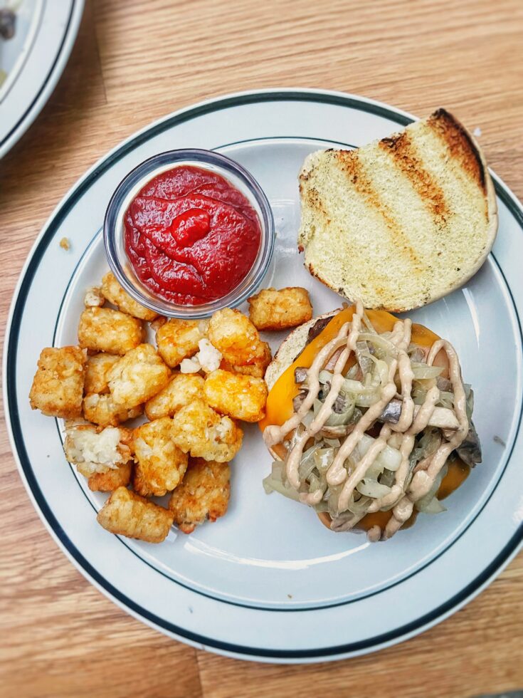 whiskey mushroom burger with tater tots on a plate